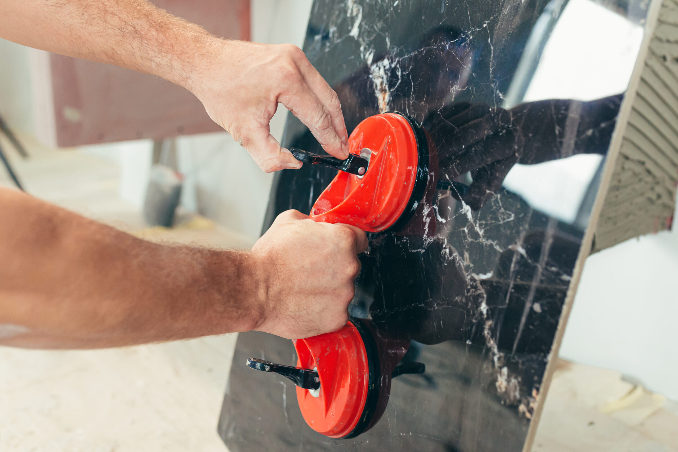 Handwerker trägt eine große Glasscheibe mithilfe eines Saugnapf-Hebers, professionelle Technik für sicheren Transport und Montage von Glas